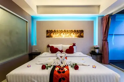 a bedroom with two beds with white sheets and red pillows at 7Q Patong Beach Hotel in Patong Beach