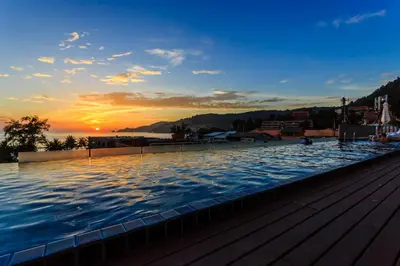 a large swimming pool with a sunset in the background at 7Q Patong Beach Hotel in Patong Beach