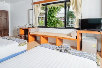 a room with two beds and a desk with a television at Karona Resort & Spa - SHA Extra Plus in Karon Beach