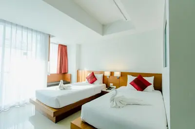 a hotel room with two beds and a window at Aspery Hotel in Patong Beach