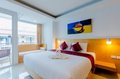 a bedroom with a large white bed and a balcony at Aspery Hotel in Patong Beach