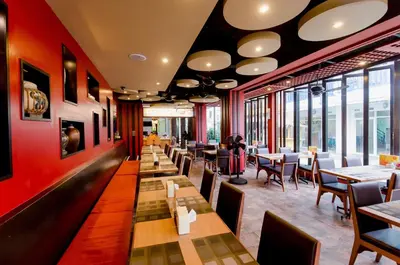 a restaurant with tables and chairs and windows at Aspery Hotel in Patong Beach