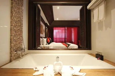 a bathroom with a bath tub with a large mirror at Rayaburi Hotel, Patong in Patong Beach