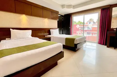 a hotel room with two beds and a window at Rayaburi Hotel, Patong in Patong Beach