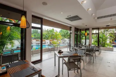 a restaurant with tables and chairs and a pool at Dewa Phuket Resort & Villas, Nai Yang Beach in Nai Yang Beach