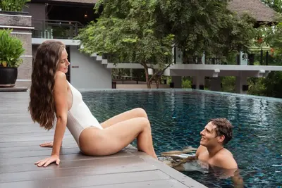 a man and a woman sitting in a swimming pool at Villa Zolitude Resort & Spa - SHA Extra Plus in Chalong