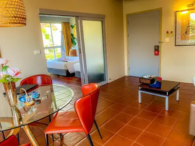 a living room with a glass table and red chairs at Sino House Phuket Hotel - SHA Plus in Phuket Town
