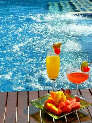 a plate of fruit and two drinks next to a pool at Ananta Burin Resort in Ao Nang Beach