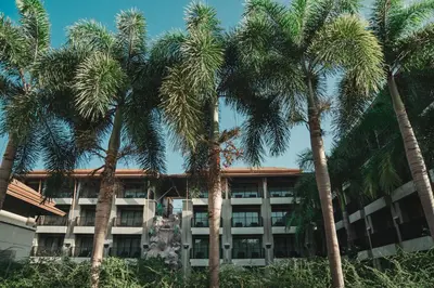 an apartment building with palm trees in front of it at Ananta Burin Resort in Ao Nang Beach