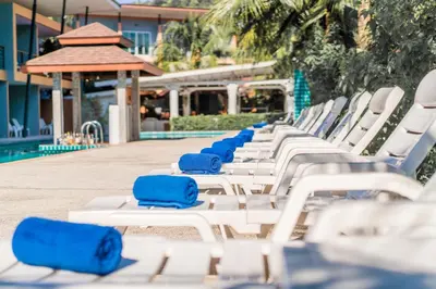 a row of white lounge chairs next to a swimming pool at Phi Phi Anita Resort in Phi Phi Don