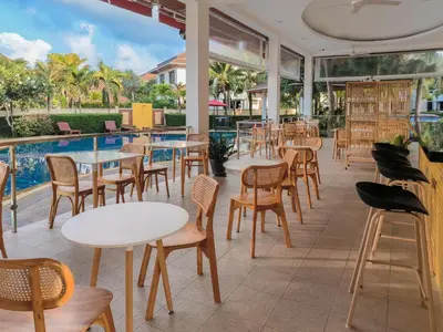 a restaurant with tables and chairs next to a pool at Rawai Grand House -SHA Plus in Rawai Beach