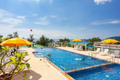 a pool with people swimming in it with umbrellas at Baumancasa Beach Resort in Karon Beach