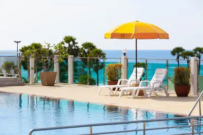 a swimming pool with two chairs and an umbrella at Baumancasa Beach Resort in Karon Beach