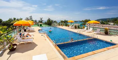 a large swimming pool with chairs and umbrellas at Baumancasa Beach Resort in Karon Beach