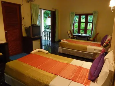 a living room with two beds and a television at Aonang Green Park Bungalow in Ao Nang Beach