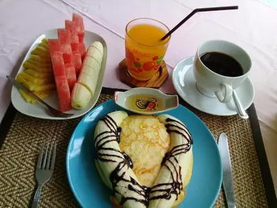 a table with a blue plate of food and a cup of coffee at Aonang Green Park Bungalow in Ao Nang Beach