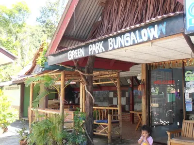 a small child standing in front of a green park building at Aonang Green Park Bungalow in Ao Nang Beach