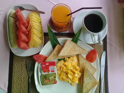 a breakfast plate with eggs toast and fruit and a cup of coffee at Aonang Green Park Bungalow in Ao Nang Beach