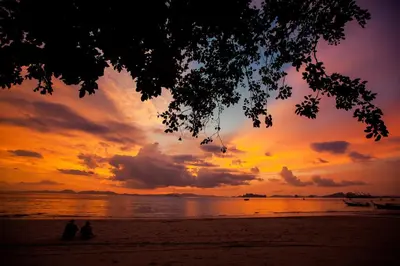 two people sitting on the beach at sunset at Klong Muang Sunset House in Klong Muang Beach