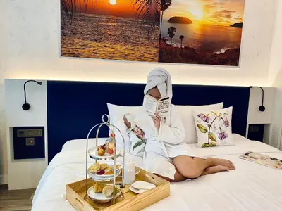 a woman laying on a bed reading a book at Hotel Clover Patong Phuket - SHA Plus in Patong Beach