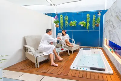 two people in white robes sitting on a deck with a hot tub at Hotel Clover Patong Phuket - SHA Plus in Patong Beach