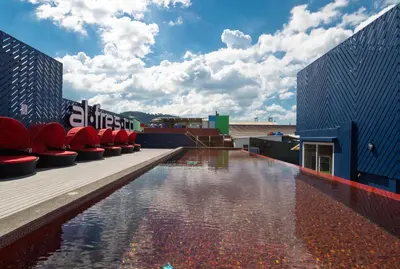 a pool on the roof of a building with red chairs at Alfresco Phuket Hotel in Patong Beach