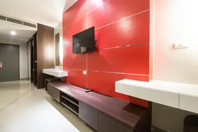 a red wall in a bathroom with two sinks and a tv at Alfresco Phuket Hotel in Patong Beach