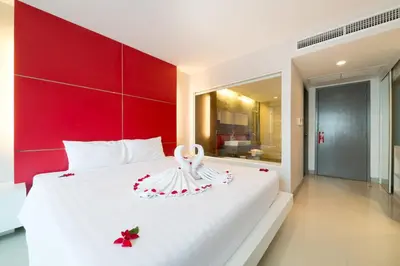 a bedroom with a white bed with a red headboard at Alfresco Phuket Hotel in Patong Beach