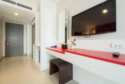 a living room with a red counter and a tv on a wall at Alfresco Phuket Hotel in Patong Beach