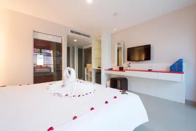 a bedroom with a white bed with roses on it at Alfresco Phuket Hotel in Patong Beach