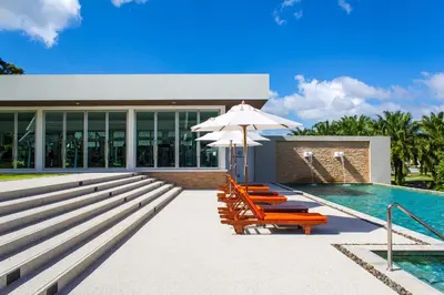 a pool with chairs and an umbrella next to a building at Tinidee Golf Resort Phuket in Kathu