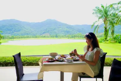 a woman sitting at a table with a plate of food at Tinidee Golf Resort Phuket in Kathu
