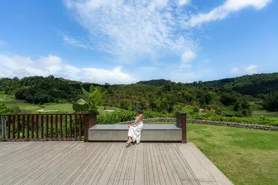 a woman sitting on a bench overlooking a golf course at Tinidee Golf Resort Phuket in Kathu