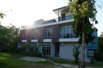 a building with a tree in front of it at Snooze Inn Phuket - Free Shuttle to Bang Rong Pier in Ban Pa Khlok