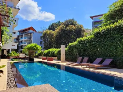 a swimming pool with lounge chairs next to a building at Surintra Boutique Resort in Surin Beach