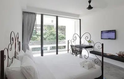 a bedroom with a large white bed and a balcony at Surintra Boutique Resort in Surin Beach