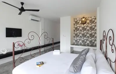 a bedroom with a white bed and a couch at Surintra Boutique Resort in Surin Beach
