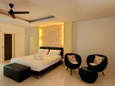 a bedroom with a bed and two chairs at Surintra Boutique Resort in Surin Beach