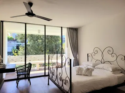 a bedroom with a bed and a table and a ceiling fan at Surintra Boutique Resort in Surin Beach