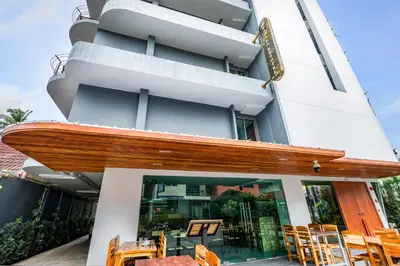 a building with a deck with tables and chairs at Kamala Resotel, SHA Extra Plus in Kamala Beach