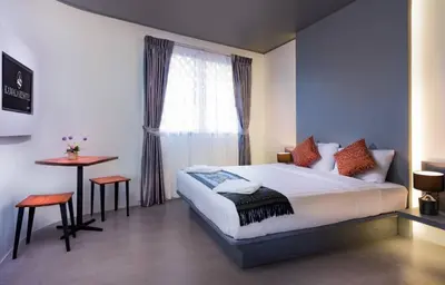 a bedroom with a bed and a table and a window at Kamala Resotel, SHA Extra Plus in Kamala Beach