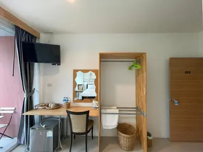 a room with a desk and a table with a mirror at Dwell Phuket Airport Hotel at Naiyang in Nai Yang Beach