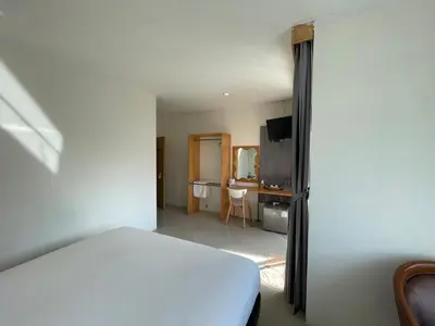 a bedroom with a bed and a desk with a television at Dwell Phuket Airport Hotel at Naiyang in Nai Yang Beach