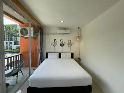 a bedroom with a white bed and a balcony at Dwell Phuket Airport Hotel at Naiyang in Nai Yang Beach