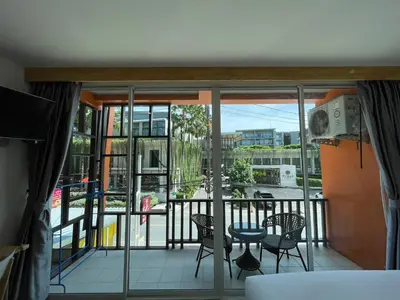 a room with a balcony with a table and chairs at Dwell Phuket Airport Hotel at Naiyang in Nai Yang Beach