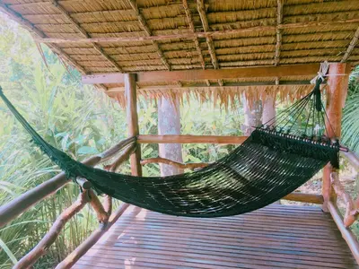 a hammock hanging from a roof in a forest at Tha Khao Bay View Bungalow in Ko Yao Noi