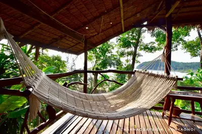 a hammock on a deck with a table at Tha Khao Bay View Bungalow in Ko Yao Noi