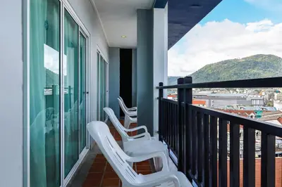 a balcony with white chairs and a view of a city at Amata Patong in Patong Beach