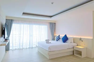 a bedroom with a white bed and a large window at Amata Patong in Patong Beach