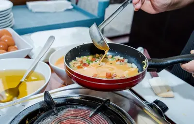 a person cooking food in a pot on a stove at ASHLEE Hub Hotel Patong in Patong Beach
